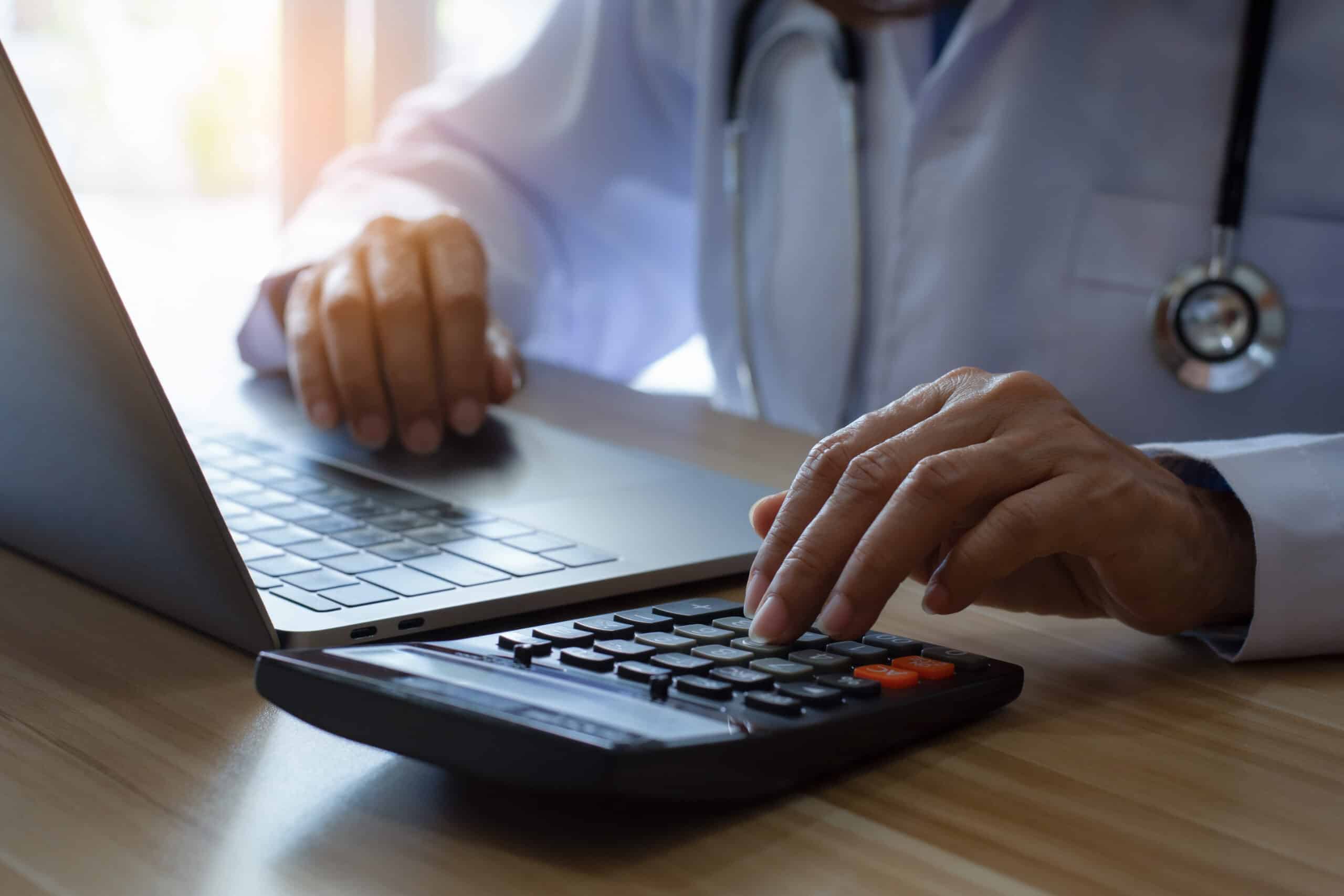 Doctor or physician using calculator and work on laptop computer