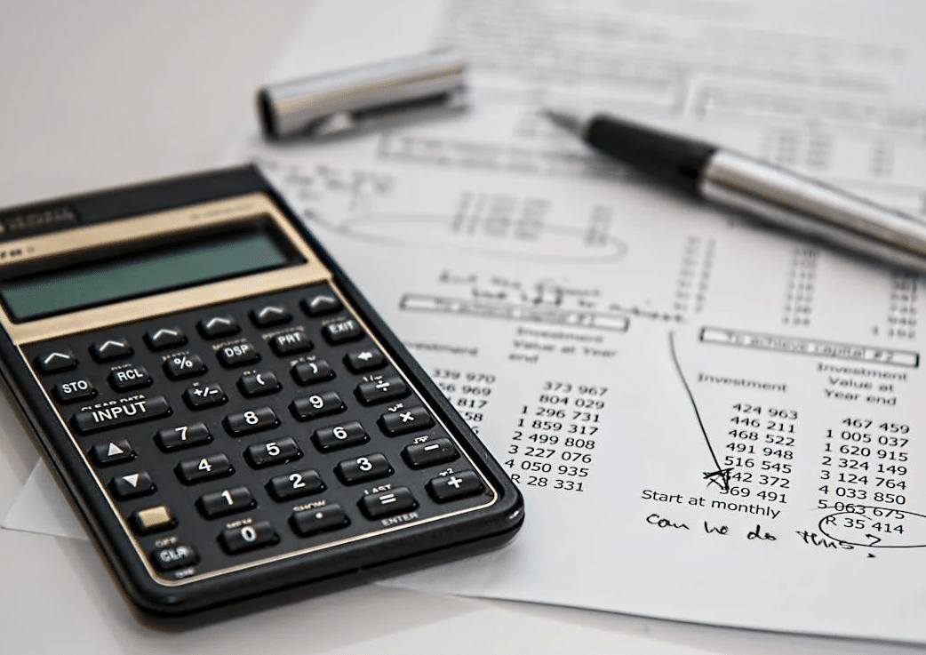 Black calculator near some cost sheets and black ballpoint pen