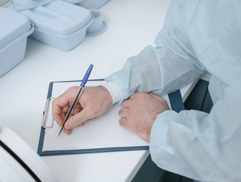Medical professional writing on clipboard on white desk